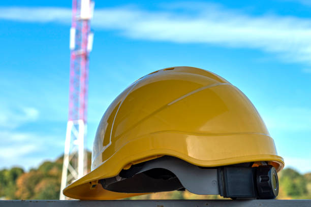 istock Yellow hard safety helmet hat with communication tower in background 1277518312