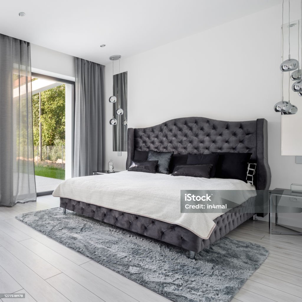 King size bed in glamorous bedroom King size, gray and quilted bed in glamorous bedroom with big window Owner's Bedroom Stock Photo