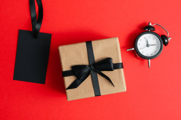istock Alarm clock, gift box and tag on red background 1277520137
