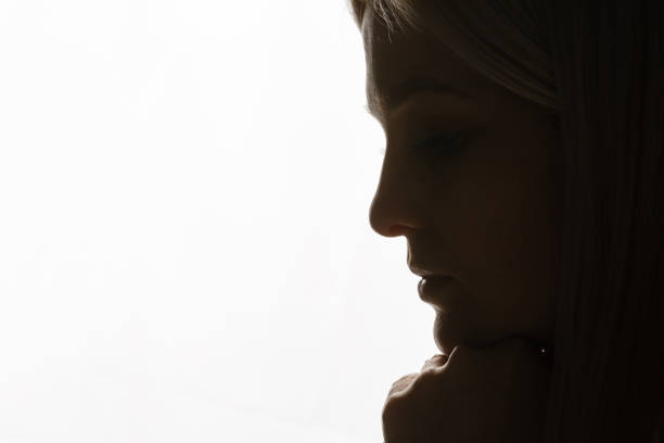 istock A young woman in prayer under dramatic light. 1277520238
