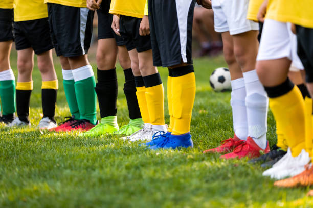 Kids on soccer training. Soccer players standing in a row. Low angle image of footballer's legs in a sportswear and cleats. Colourful soccer clothing Kids on soccer training. Soccer players standing in a row. Low angle image of footballer's legs in a sportswear and cleats. Colourful soccer clothing football socks stock pictures, royalty-free photos & images