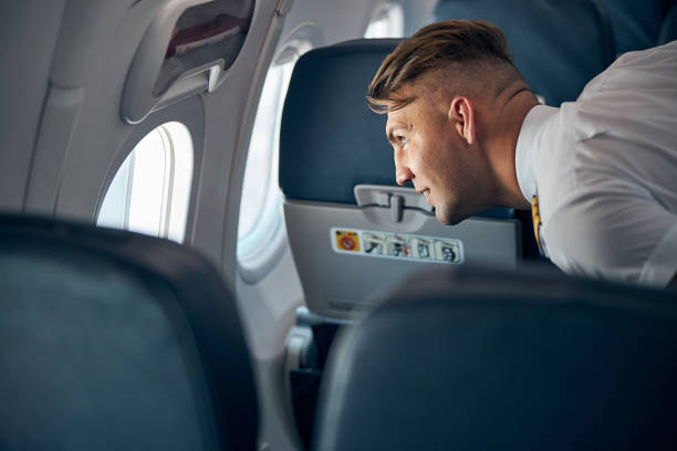 istock Smiling man in uniform standing at the illuminator in airplane 1277521781