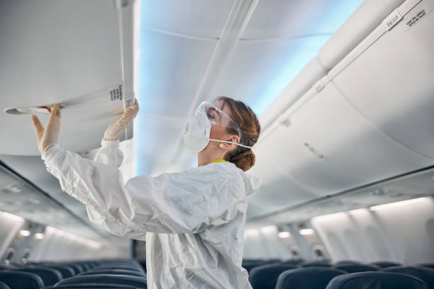 istock Female air hostess in white uniform closing cabin compartment 1277521822