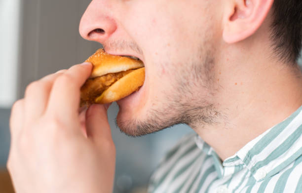 istock A man eats junk food, a close-up. Guy bites chicken burger 1277523079