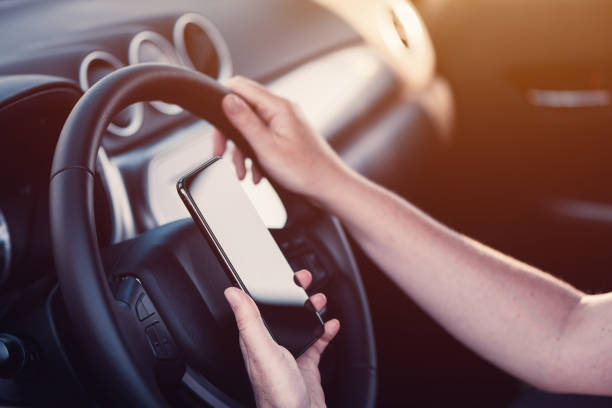 istock Woman texting on mobile phone in the car while holding steering wheel 1277524428