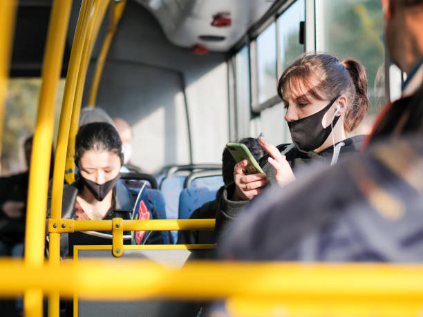 Selective focus on a young girl in a protective mask in a city bus. A protective mask is on the passenger's face. Moscow. Russia. September 24, 2020. Selective focus on a young girl in a protective mask in a city bus. A protective mask is on the passenger's face. The girl holds a smartphone and listens to music. vehicle interior audio stock pictures, royalty-free photos & images