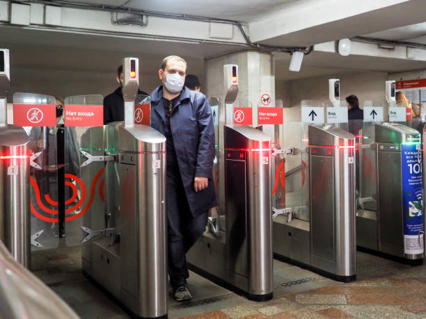 les passagers masqués passent par des tourniquets automatiques dans une station de métro. - train railroad station platform railroad station vehicle door photos et images de collection