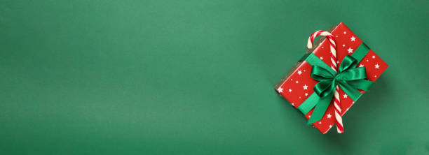 istock Christmas box with candy cane on green background 1277527595