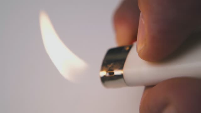 man burns plastic lighter by finger on white background