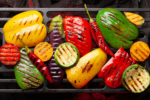 Grilled vegetables cooking on coal grill with spices and herbs. Top view flat lay