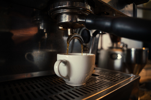 Close up of coffee machine producing espressos for customers in funky cafe