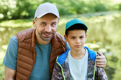 Portrait of loving father and son looking at camera while enjoying camping trip together in nature