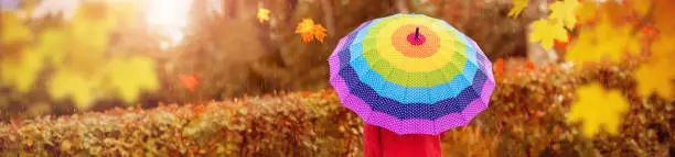 Child outdoors on rainy weather. Boy holding colorful umbrella under rain in autumn.