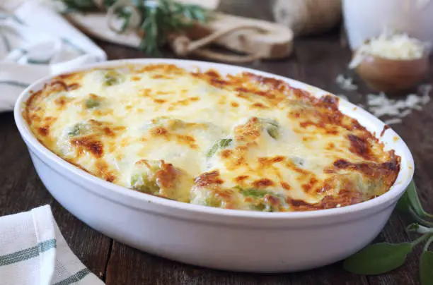 Vegetable Brussels sprouts gratin with cheese in ceramic bakeware on wooden table