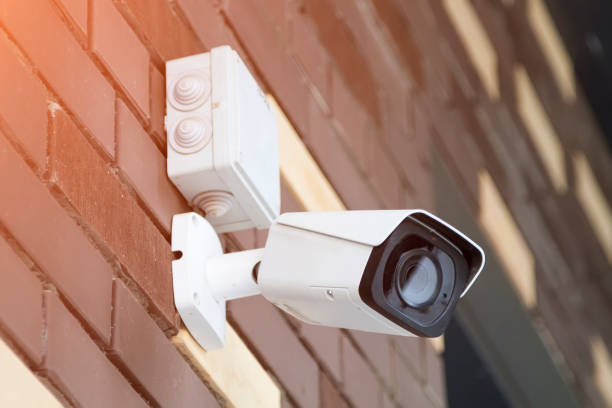 istock Closed-circuit television camera mounted on brick wall. CCTV security camera outdoors. 1277535056