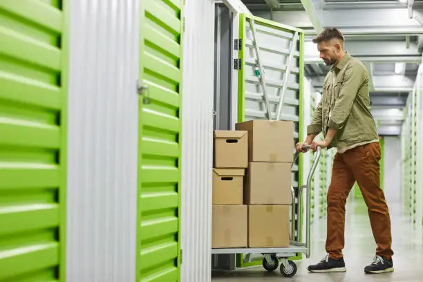 Photo of Man Moving Boxes in Storage Unit