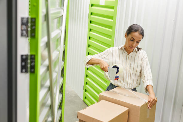istock Woman Packing Boxes in Storage Facility 1277536130