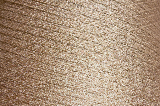 beige background. Texture of a large bobbin of coiled thread.