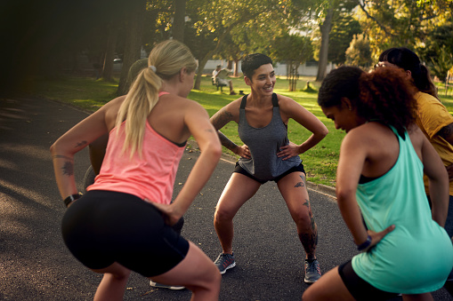 Shot of a group of young women doing squats during their workout in a park