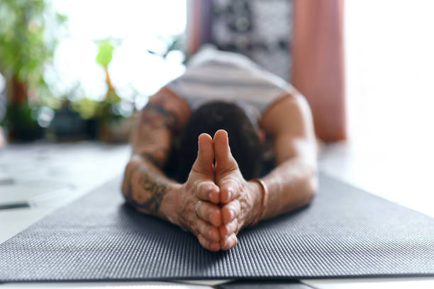 You can't change the world but you can change yours Shot of a young man going through a yoga routine at home yoga stock pictures, royalty-free photos & images