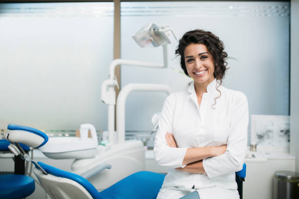 portrait of a caucasian female dentist in her office - dentists chair fotos imagens e fotografias de stock