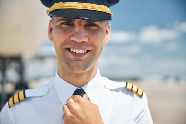 istock Cheerful pilot in command adjusting his tie at airport 1277540614