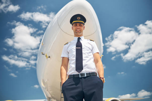 istock Cheerful male pilot standing under blue sky 1277540618