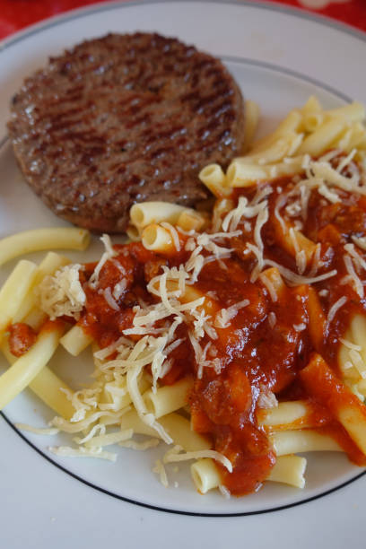 steak haché frit servi avec sauce tomate aux pâtes macaronis - macaroni cheese food staple casserole photos et images de collection