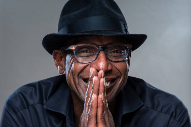 istock Real Man with cheerfull Expression. Portrait of a real man with black hat on a gray background. 1277541908