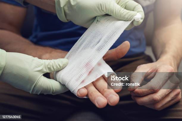 First Aid Doctor Traumatologist Bandaging Patient Injured Hand Stock Photo - Download Image Now