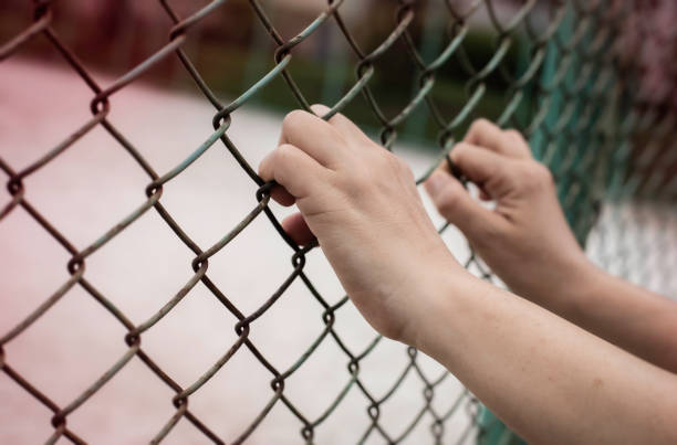 istock Human hand catch iron chainlink fence,blurry light around 1277543714