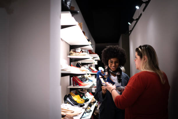 junge frau wird von einer verkäuferin beim einkaufen für schuhe in einem sparsamen geschäft geholfen - shoe store sales clerk customer stock-fotos und bilder