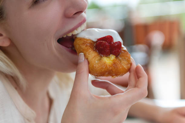 Young woman bites strawberry danish pastry