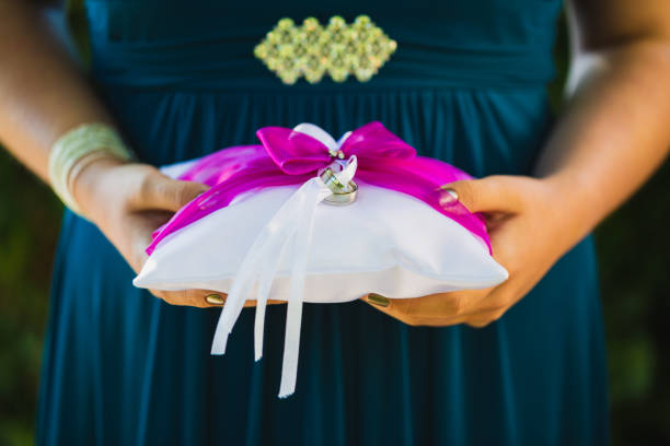 Female hands holding wedding rings on a cushion, selective focus