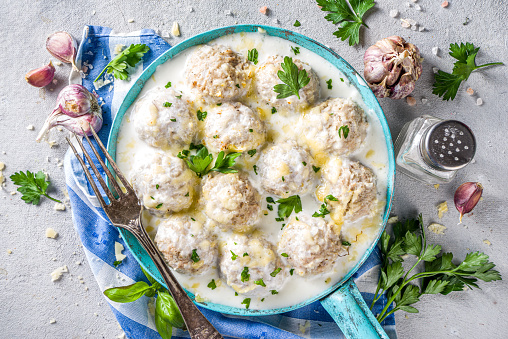 Homemade creamy white chicken meatballs. Classic Swedish meatballs with creamy cheesy sauce, with parmesan cheese and parsley, in skillet on grey stone table background