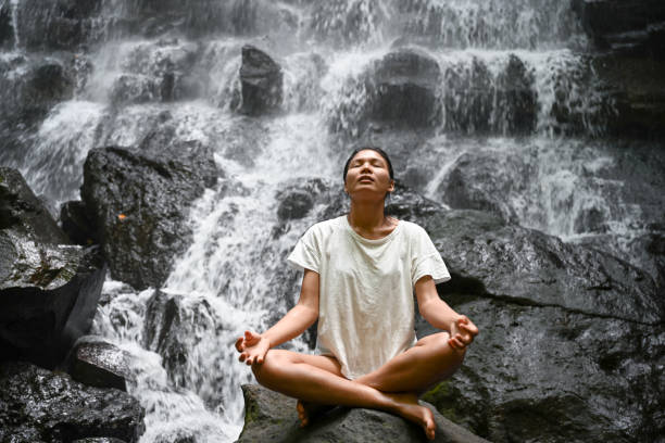 istock Woman meditating in front of the waterfall 1277546880
