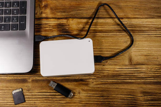 istock External HDD connected to laptop computer, SD memory card and USB flash drive on a wooden desk. Top view. Concept of data storage 1277548379