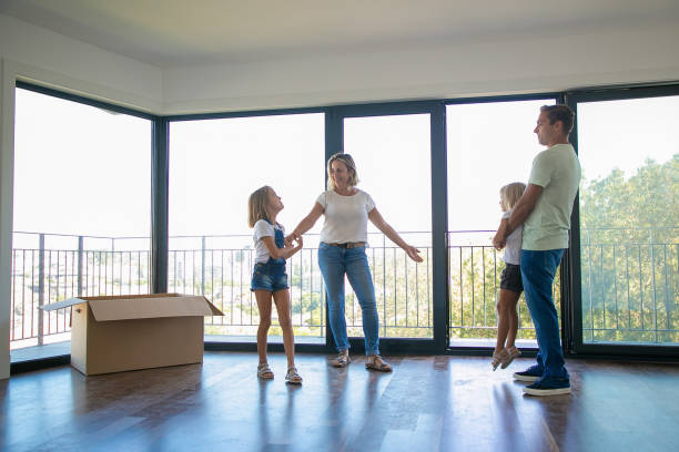 istock Mother, father and two daughters standing in empty living room 1277553949