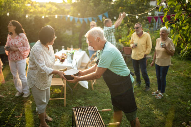 Senior friends enjoying quality time together at backyard during beautiful day Senior friends enjoying quality time together at backyard during beautiful day neighbour stock pictures, royalty-free photos & images