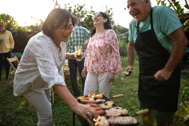 istock Senior man making barbeque for his friends during party at backyard 1277558130