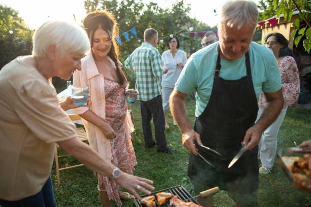 istock Senior man making barbeque for his friends during party at backyard 1277559020
