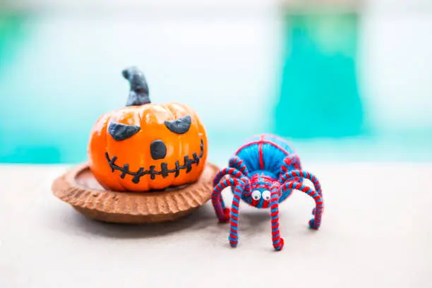 Photo of Happy Halloween background, smiling halloween pumpkin with blue and red yarn spider over blurred background