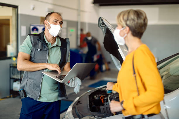 istock Auto mechanic using laptop while talking to a customer in repair shop. 1277559871