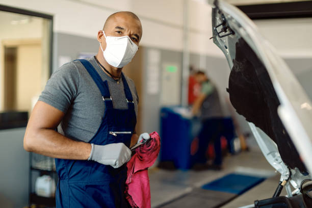 istock Black auto repairman wearing protective face mask while working in a workshop. 1277560145