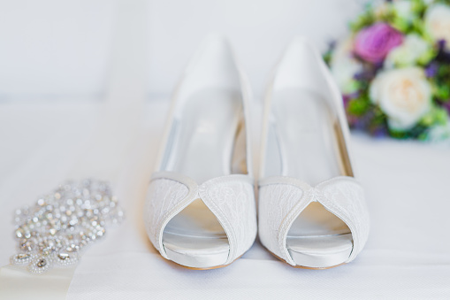 Bridal shoes with the wedding bouquet in the background, selective focus