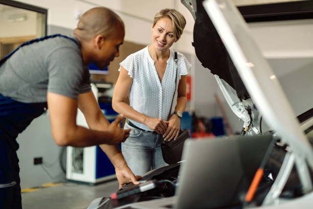 修理店で彼女の車の整備士と話す幸せな女性。 - mechanic auto repair shop auto mechanic repairing ストックフォトと画像