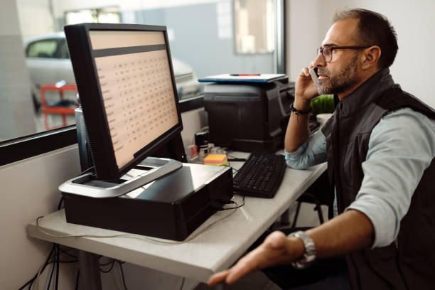 istock Foreman of auto mechanic workshop talking on the phone while using computer in the office. 1277561971