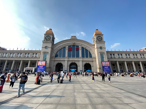 Wuhan/China-Oct.2020 Facade of Hankou Railway Station on sunny day. Travellers wearing face mask to prevent coronavirus, walking on square