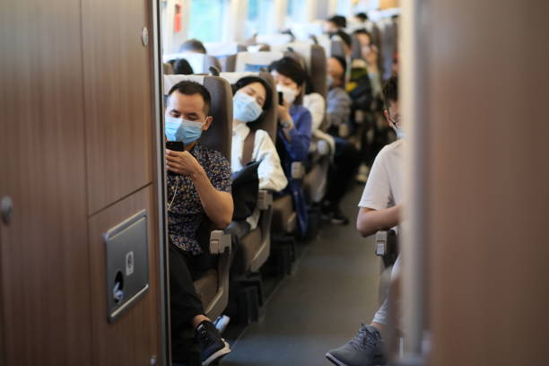 Cheerful Asian passenger wearing hat looking out of train window