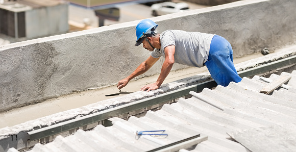 Shot of a mason worker wearing hardhat constructing a rooftop with concrete